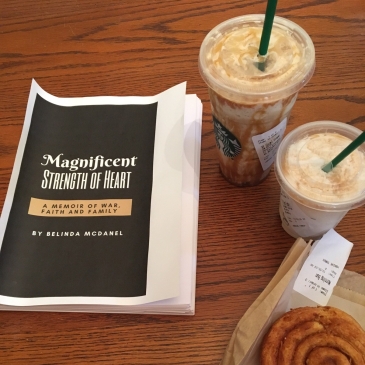 Next to two Starbucks drinks and a morning bun is the manuscript of a book. Title: Magnificent Strength of Heart: A memoir of war, faith and family by Belinda McDanel